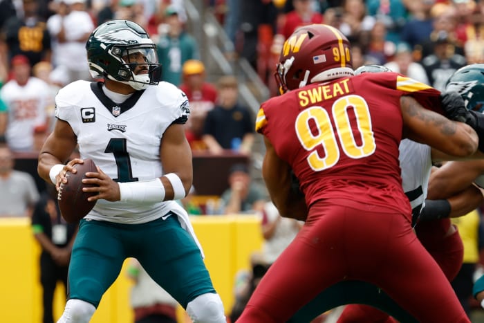 Philadelphia Eagles quarterback Jalen Hurts (1) prepares to pass the ball as Washington Commanders defensive end Montez Sweat (90) chases during the first quarter at FedExField.